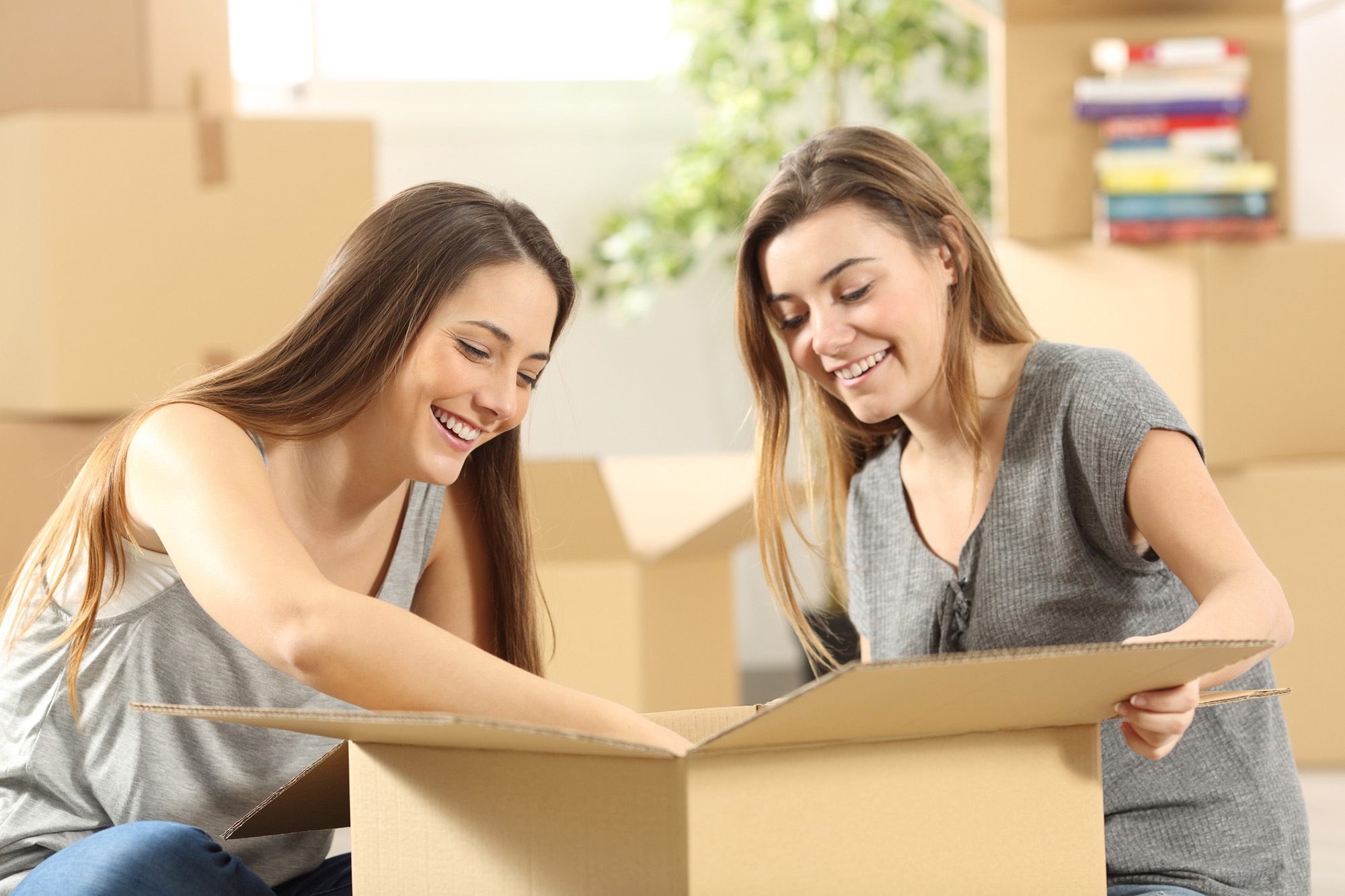 Two young women unpacking a box together.