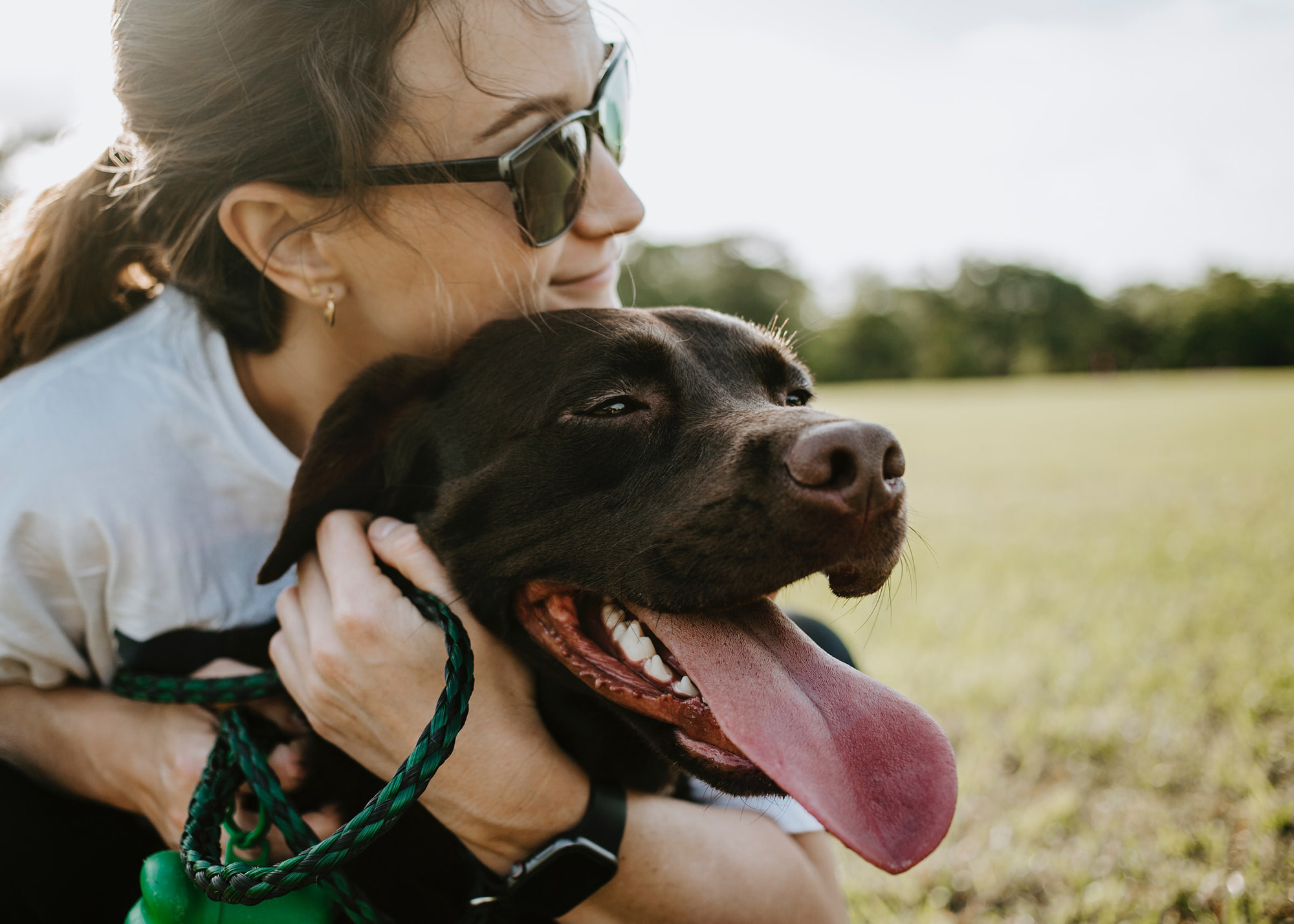 Close-up of woman hugging black dog.