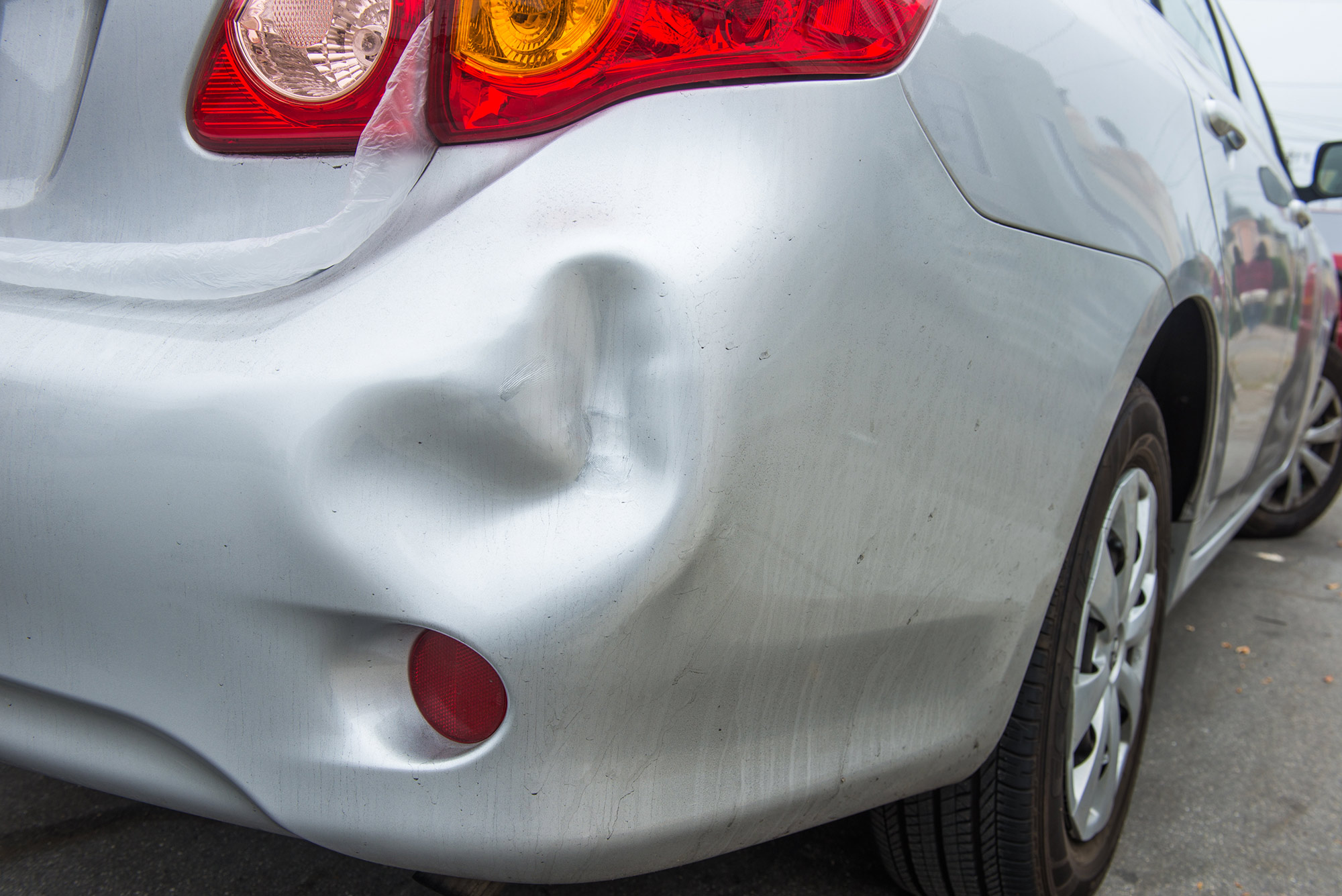 Close up of dented bumper on a vehicle.