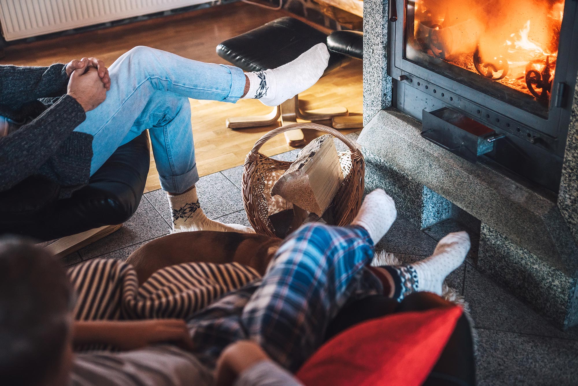 Person relaxing in front of a cozy fire in their fireplace at home.