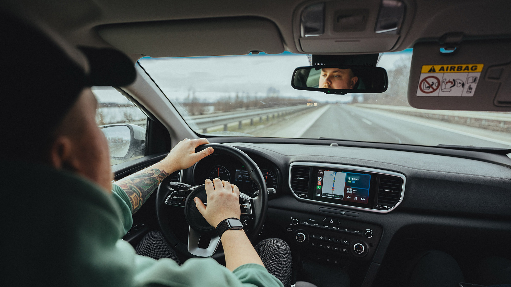 Over-the-shoulder view of man driving a vehicle.