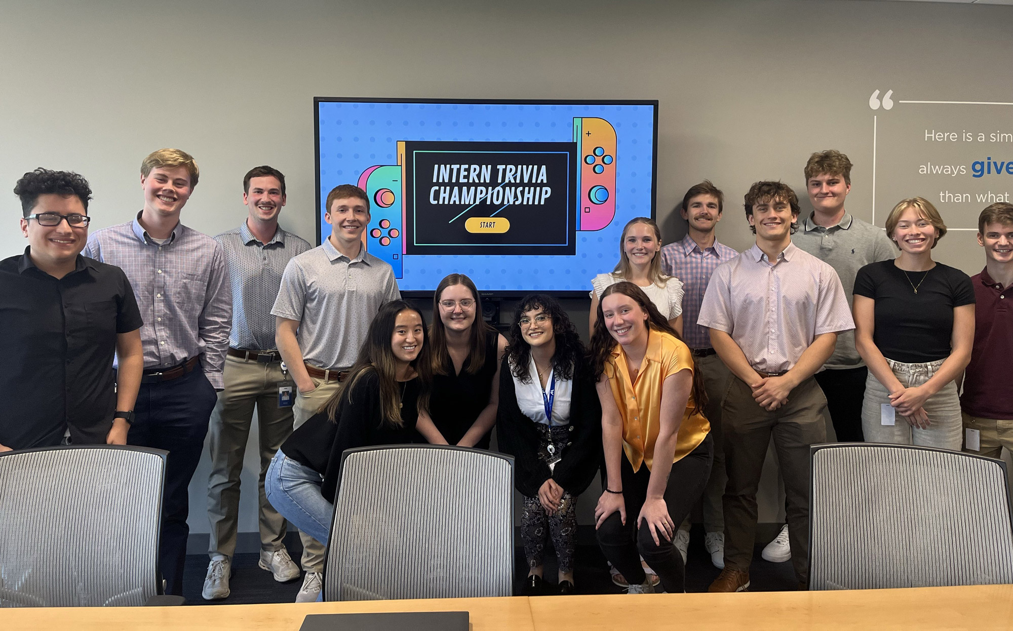 A group of interns standing in front of a tv monitor