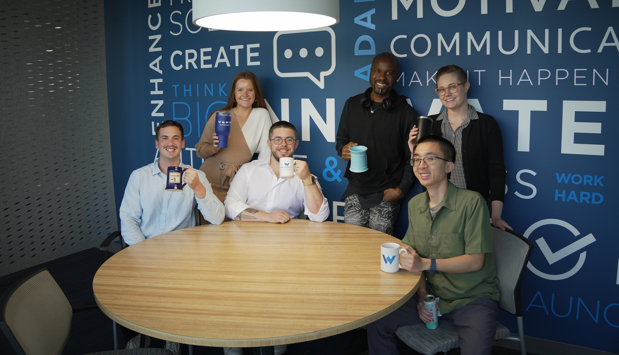 Group of Western National Employees posting with mugs smiling at the camera.