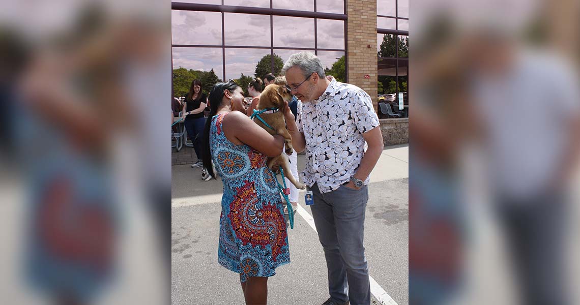 Candid shot of Western National's President and CEO, Rick Long, leaning in to give attention to a fuzzy puppy in an emplpyee's arm.